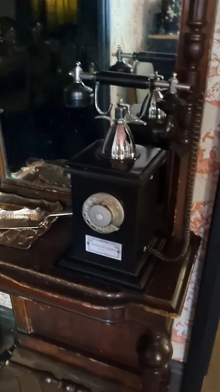 An antique telephone on a carved wooden stand