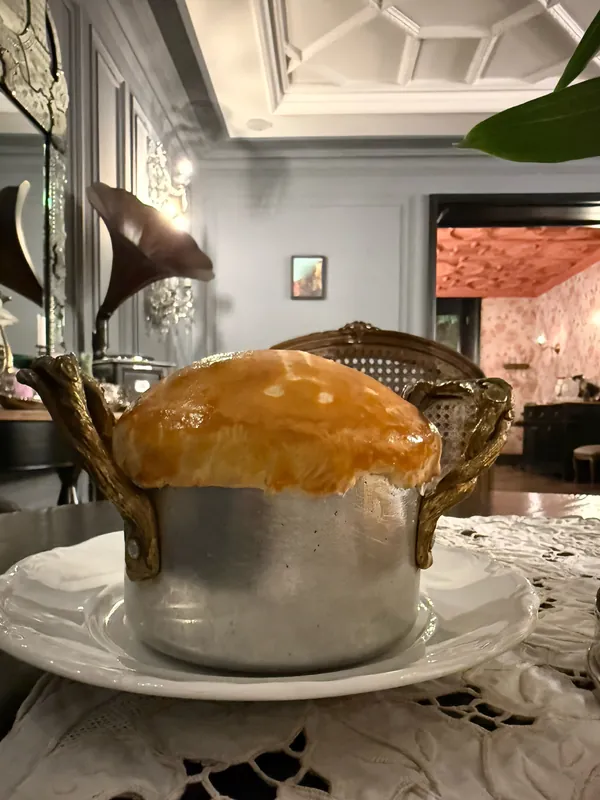 A small pot baked under a golden pastry lid on a lace tablecloth