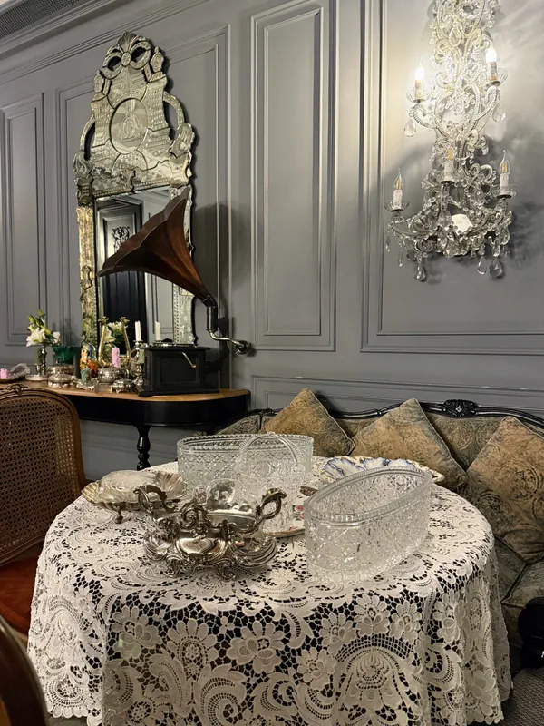 A lace-covered table under a Venetian-style mirror, with a gramophone